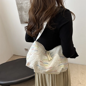 White rhythmic striped embroidered canvas hobo bag with textured pattern shown on model