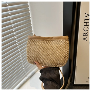 Detail of straw woven crossbody bag featuring light beige fiber texture and brown leather strap