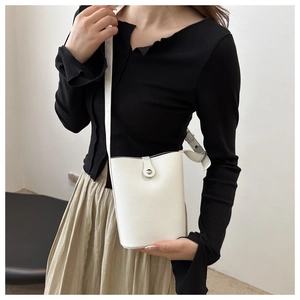 Detailed view of white litchi pattern leather bucket bag with silver metal snap buckle