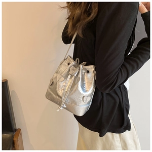 Detail of silver drawstring bucket bag with embossed 3D heart-shaped patches and shiny finish