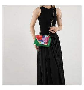 Détail du patchwork géométrique coloré et chaîne dorée fine sur sac à bandoulière vif