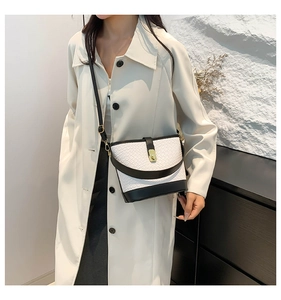 Detail of fashion woven shoulder bag featuring black leather trim and gold twist lock