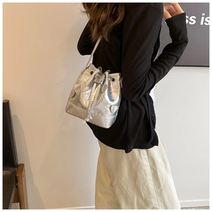 Detail of silver metallic bucket bag with heart embossed pattern and drawstring closure