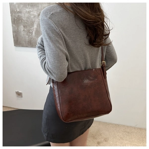 Close-up of vintage dark brown faux leather bucket bag with adjustable metal buckle strap
