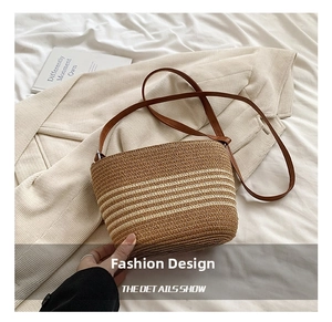 Detail of handwoven straw bucket bag with striped pattern and brown leather strap