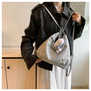 Détail du sac bandoulière argenté brillant avec papillons et breloque nuage sur le modèle