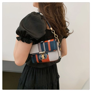 Détail du sac à bandoulière à carreaux colorés avec fermoir doré sur robe noire