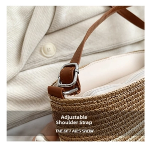 Detail showing adjustable brown leather strap and silver metal buckle of straw bag