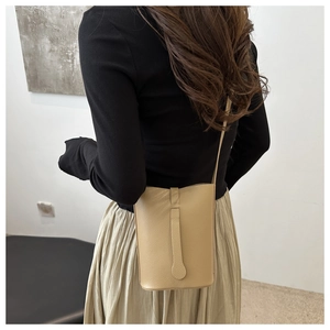 Detailed view of cream leather crossbody bag with decorative strap and textured finish