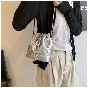Silver PU leather drawstring bucket bag with metallic heart accents shown on person