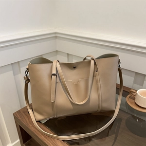 Minimalist beige soft leather tote bag with shoulder strap and front pocket on desk