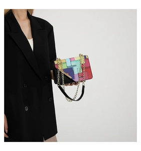 Detail of color-block geometric crossbody bag with gold chain strap on black blazer