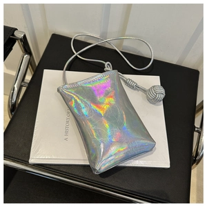 Détail du sac de téléphone holographique argenté avec bandoulière tissée et nœud boule