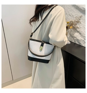 Detail of contrast stitching and gold metal buckle on a black and white bucket bag