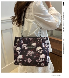Close-up of skull and flower print on canvas tote bag with chain strap and logo