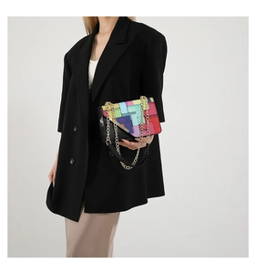 Detail of colorful patchwork shoulder bag with chunky gold chain strap and flap closure