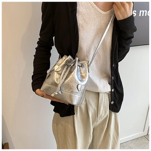Detail of silver metallic drawstring bucket bag with heart charms and pleated texture