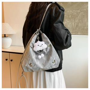 Détail du sac cabas papillon argenté avec texture plissée et charm nuage peluche