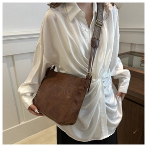 Detail of vintage brown leather tote bag with wide woven strap and gold metal buckle