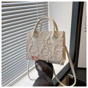 Detailed close-up of cream denim crossbody bag with quilted fringe texture and round handles