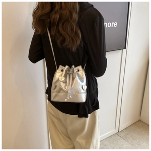 Silver drawstring bucket bag with heart patch shown on model back in a stylish pose
