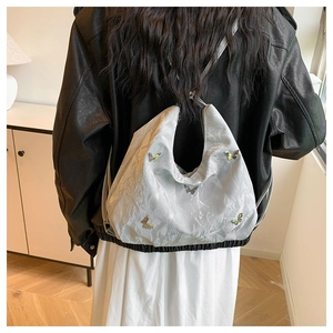 Détail de l'ornement papillon argenté sur un sac hobo plissé à effet métallique argenté