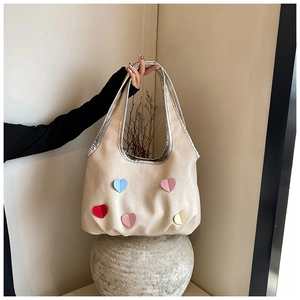 Detail der Canvas-Tasche mit bunten Herzmotiven und glänzenden silbernen Kanten