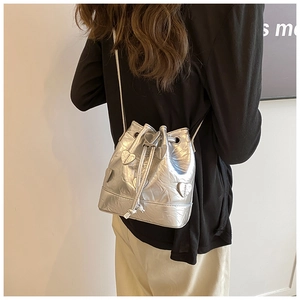 Detail of silver metallic drawstring bucket bag with heart patches shown on a model
