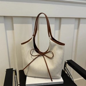 Chic canvas tote bag with brown leather trim and delicate ribbon bow accent