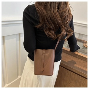 Close-up of brown litchi pattern leather bucket bag with vertical long buckle detail