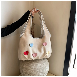 Detailaufnahme der beige gewebten Tragetasche mit bunten Herz-Patches und Silberbesatz