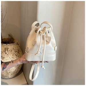 Detail of white drawstring bucket bag with textured leather and 3D heart-shaped patches