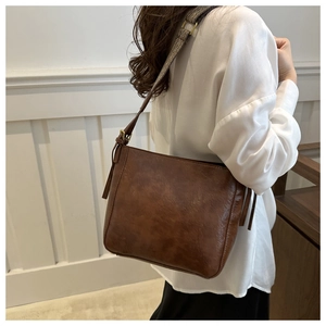 Close-up of the woven shoulder strap and golden metal buckle on a brown bucket bag