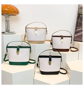 Detail of four colorful bucket bags with gold twist locks on minimalist pedestals