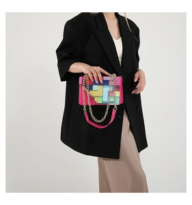 Détail du sac bandoulière color-block avec chaîne dorée sur mannequin en blazer noir