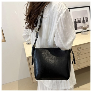 Detail of black vintage tote bag with decorative side ties and ethnic woven shoulder strap