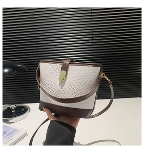 Detail of white crocodile texture bucket bag with brown leather strap and gold clasp
