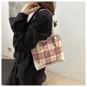 Détail du sac cabas à carreaux rouge et gris avec broderie nœud rose et bordure en cuir