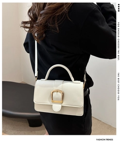 Petit sac carré beige tendance avec boucle dorée porté à l'épaule par un mannequin