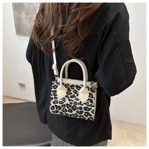 Detail of mini leopard print tote bag featuring ivory handles and gold metal hardware