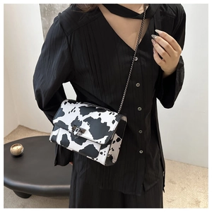 Cow print square shoulder bag with gunmetal chain strap shown on model in minimalist setting
