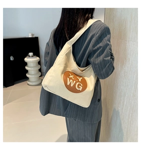 Minimalist canvas shoulder bag in cream with leather patch shown on model for size reference