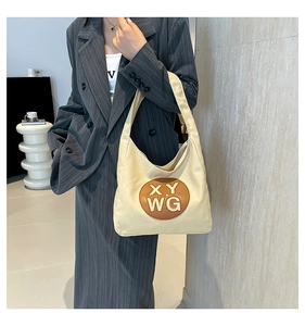 Detail of canvas tote bag with brown leather patch on a model in gray striped suit