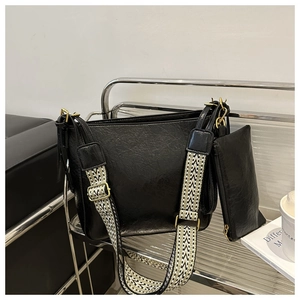 Detail of vintage black bucket bag with textured leather and patterned strap