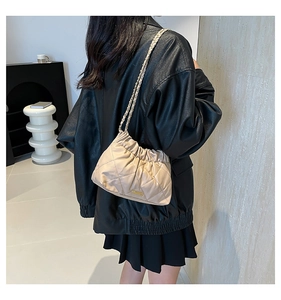 Dettaglio della borsa a secchiello trapuntata beige con catena in pelle e metallo