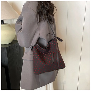Elegante borsa a secchiello nera a pois rossi con fiocco decorativo indossata dal modello