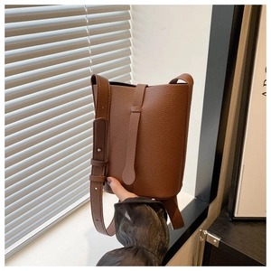 Detail of brown litchi grain leather bucket bag with decorative buckle and strap