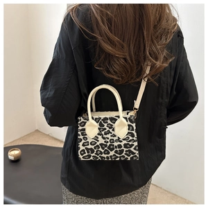 Rear view of a model wearing the small leopard print crossbody bag with cream-colored straps