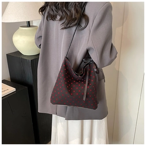 Borsa a secchiello con cuori rossi indossata da una modella in un ambiente minimal
