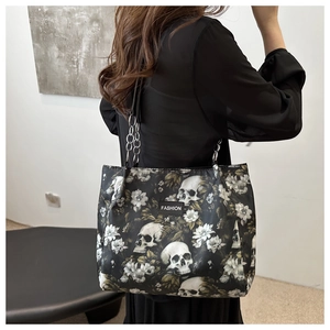 Détail du sac cabas en toile avec imprimés tête de mort et fleurs et chaîne en métal